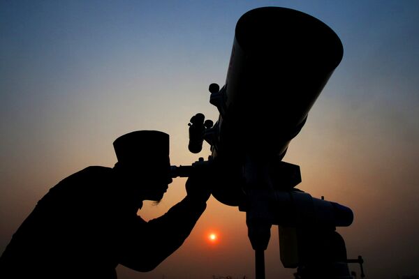 Улемы с помощью телескопа наблюдают за появлением новой луны, чтобы объявить начало священного месяца Рамадан
