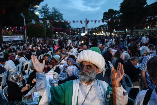 Мужчина в одежде в османском стиле радуется разговению мусульман в Голубой мечети Стамбула