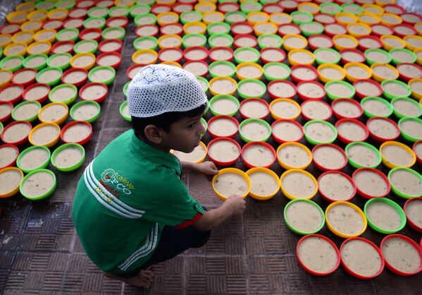 Индийский мальчик готовит длинные ряды тарелок с едой для Ифтара