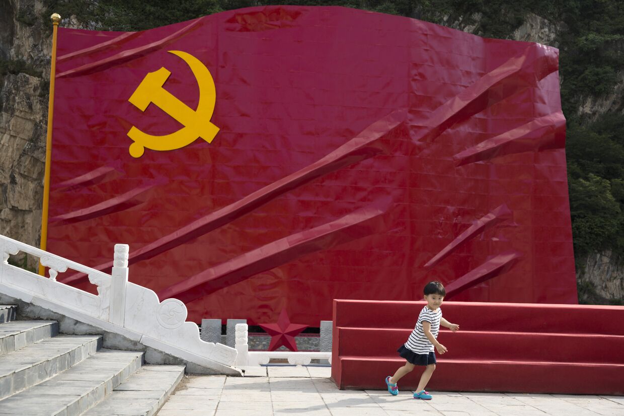 Ребенок на фоне флага Коммунистической партии Китая. 2016 год