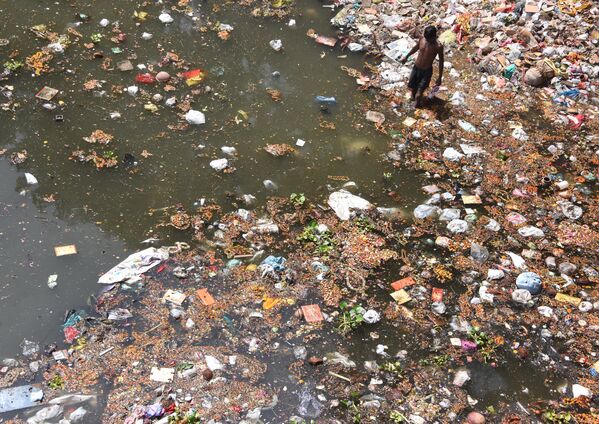 Индийский мусорщик в загрязненной реке Ямуна на окраине Нью-Дели