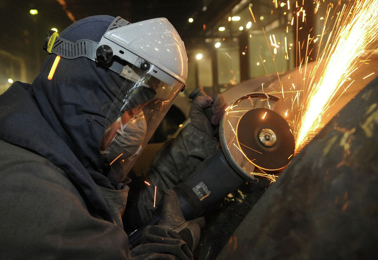 Рабочий во время обработки изделий на сталелитейном производстве