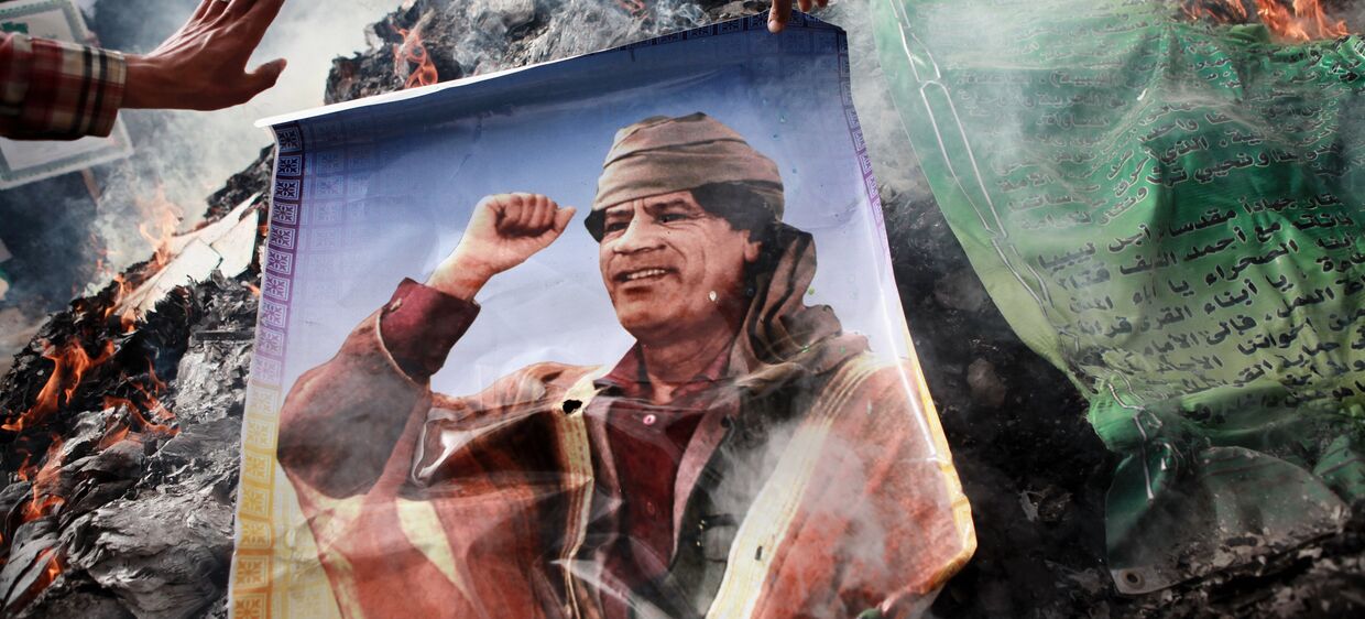 Портрет Муамара Каддафи, плакаты с его цитатами и Зеленая книга Каддафи