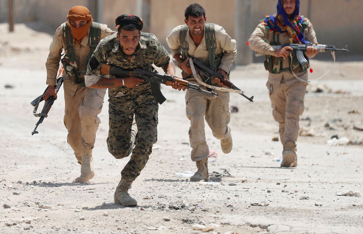 Курдские бойцы пробегают через улицу в Ракке 3 июля 2017