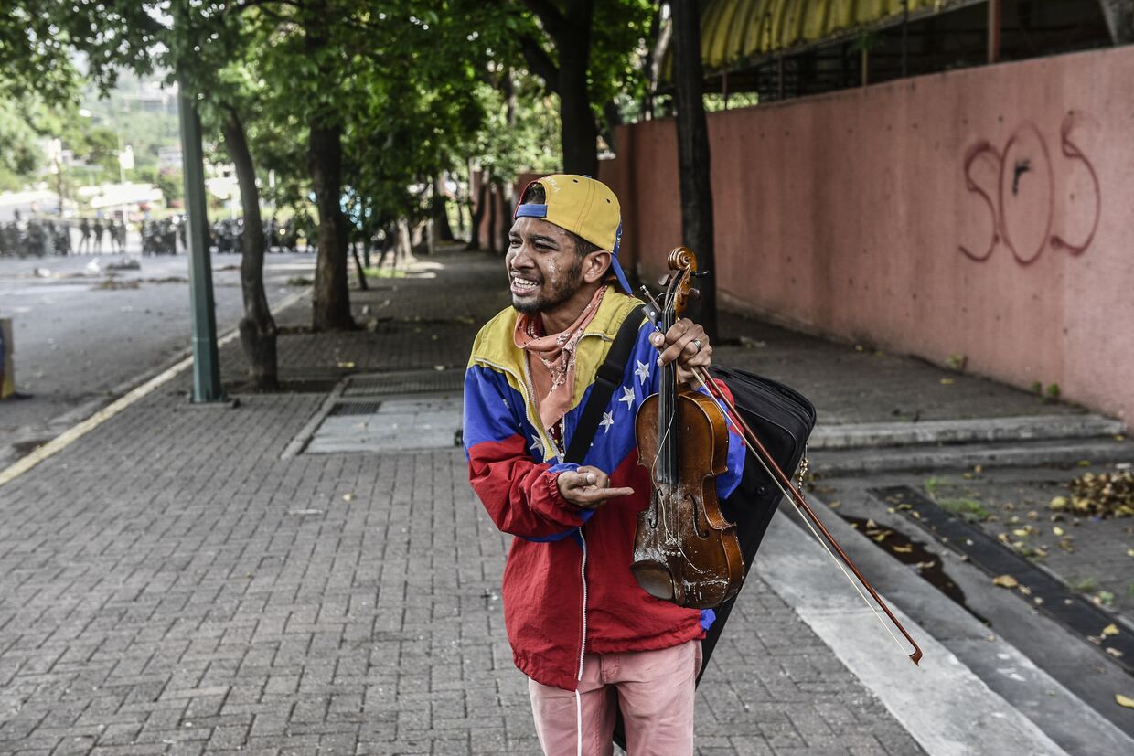 Оппозиционный активист Вилли Артеаги показывает сломанную скрипку во время акции протеста в Каракасе
