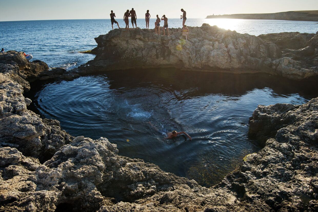 Отдыхающие у природного бассейна Чаша любви на мысе Тарханкут в Крыму