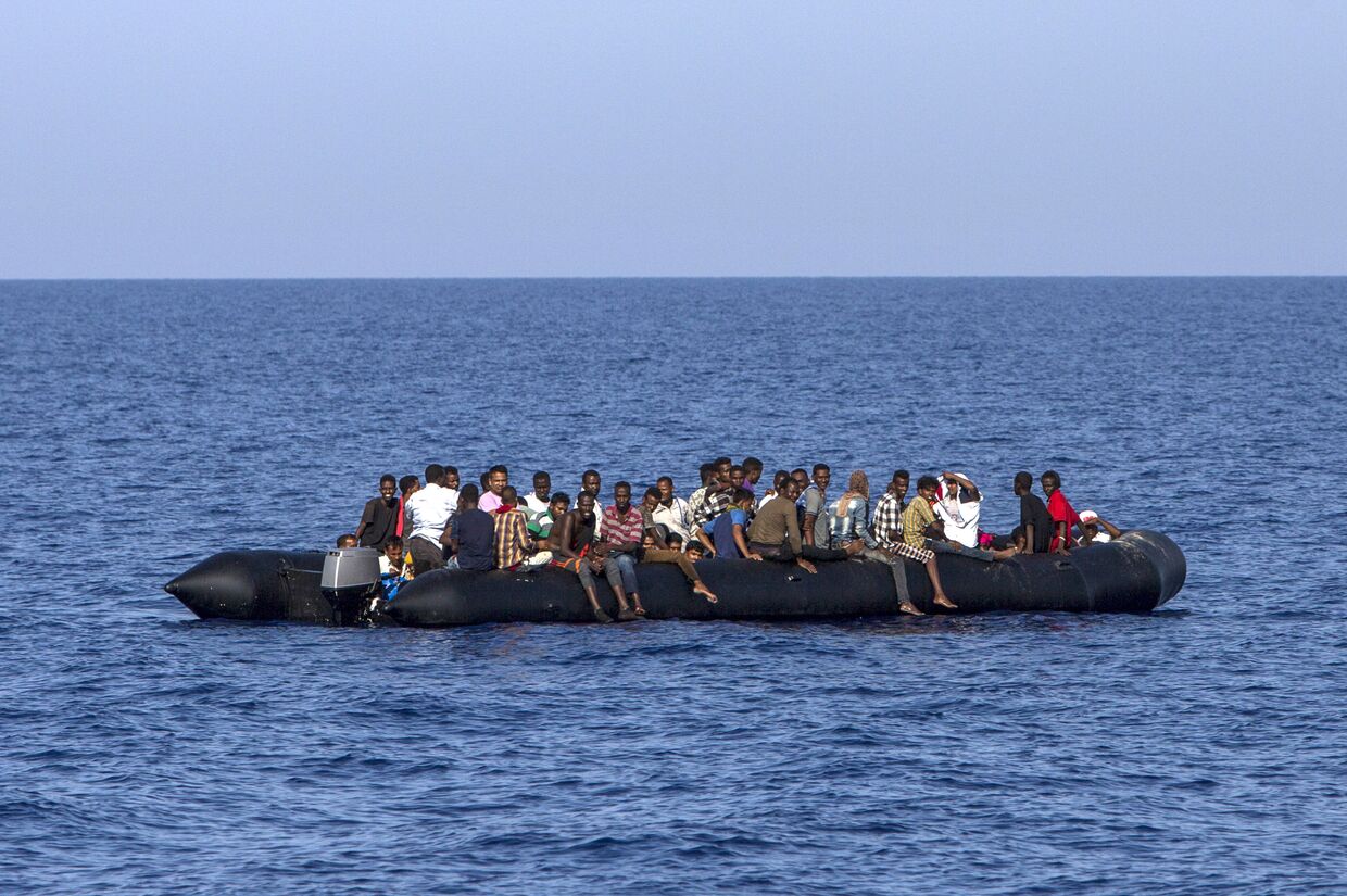 Мигранты около ливийского побережья ждут спасения итальянской береговой охраны. 6 августа 2017