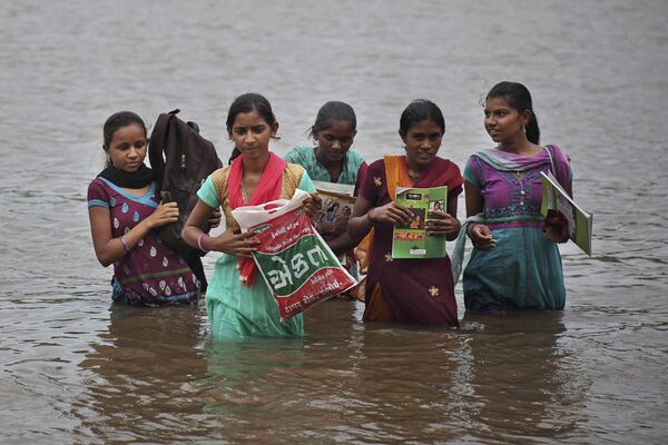 Индийские девочки пересекают реку Херана на пути из школы домой в деревне Севада в Индии