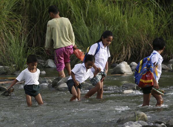 Школьникам из филиппинской деревни приходится переходить реку вброд на пути в школу