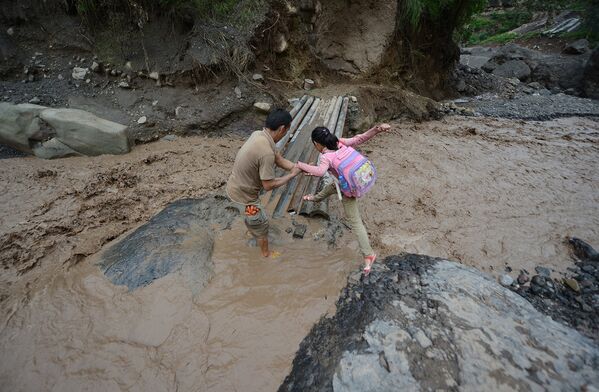 Девочка преодолевает грязевой оползень на пути в школу в китайской провинции Сычуань