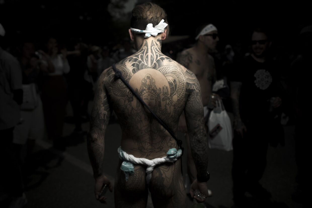 Мужчина с традиционной татуировкой якудза Ирезуми на фестивале Сандзя-мацури в Токио