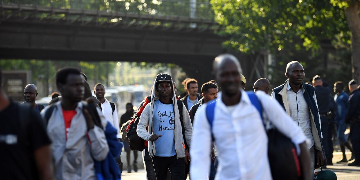 Беженцы во время эвакуации из импровизированного лагеря в Порт-де-ла-Шапель, на севере Парижа
