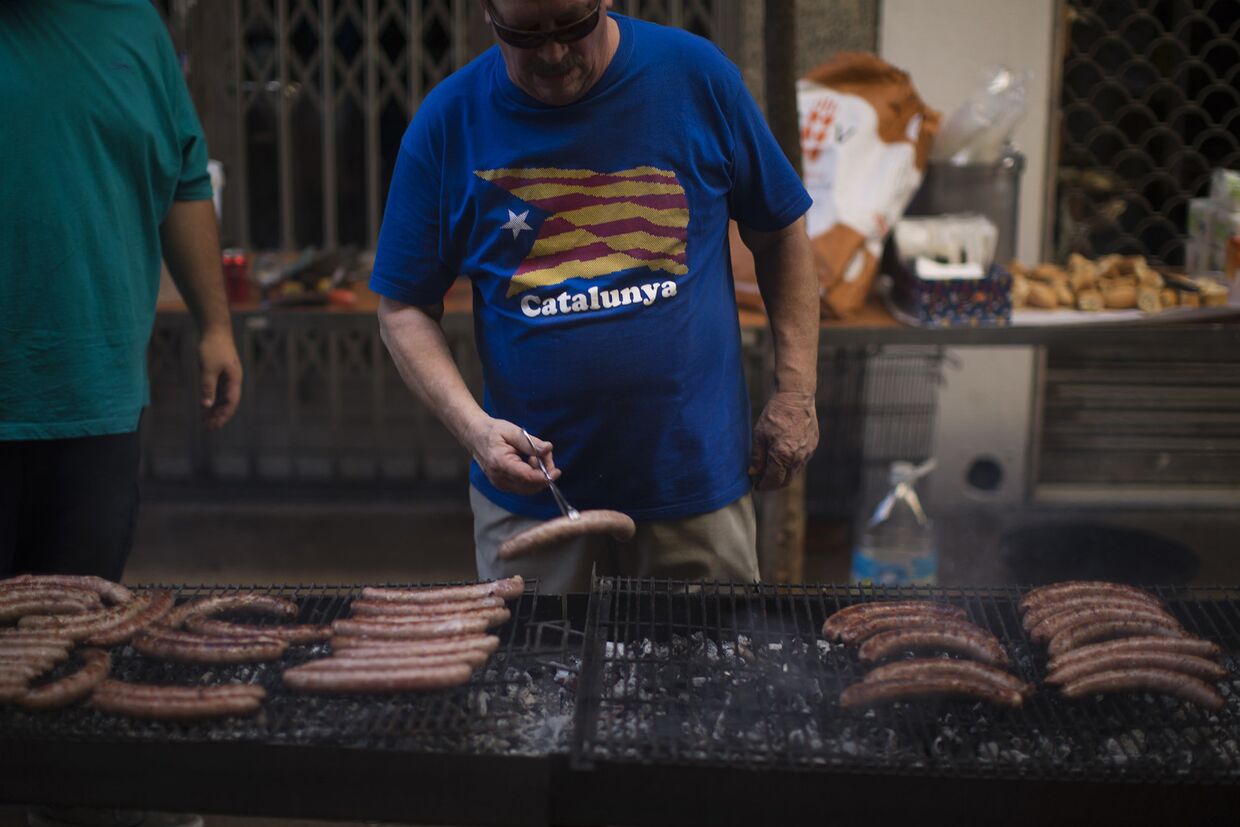 Мужчина жарит сосиски в Национальный день Каталонии в Барселоне
