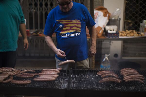 Мужчина жарит сосиски в Национальный день Каталонии в Барселоне