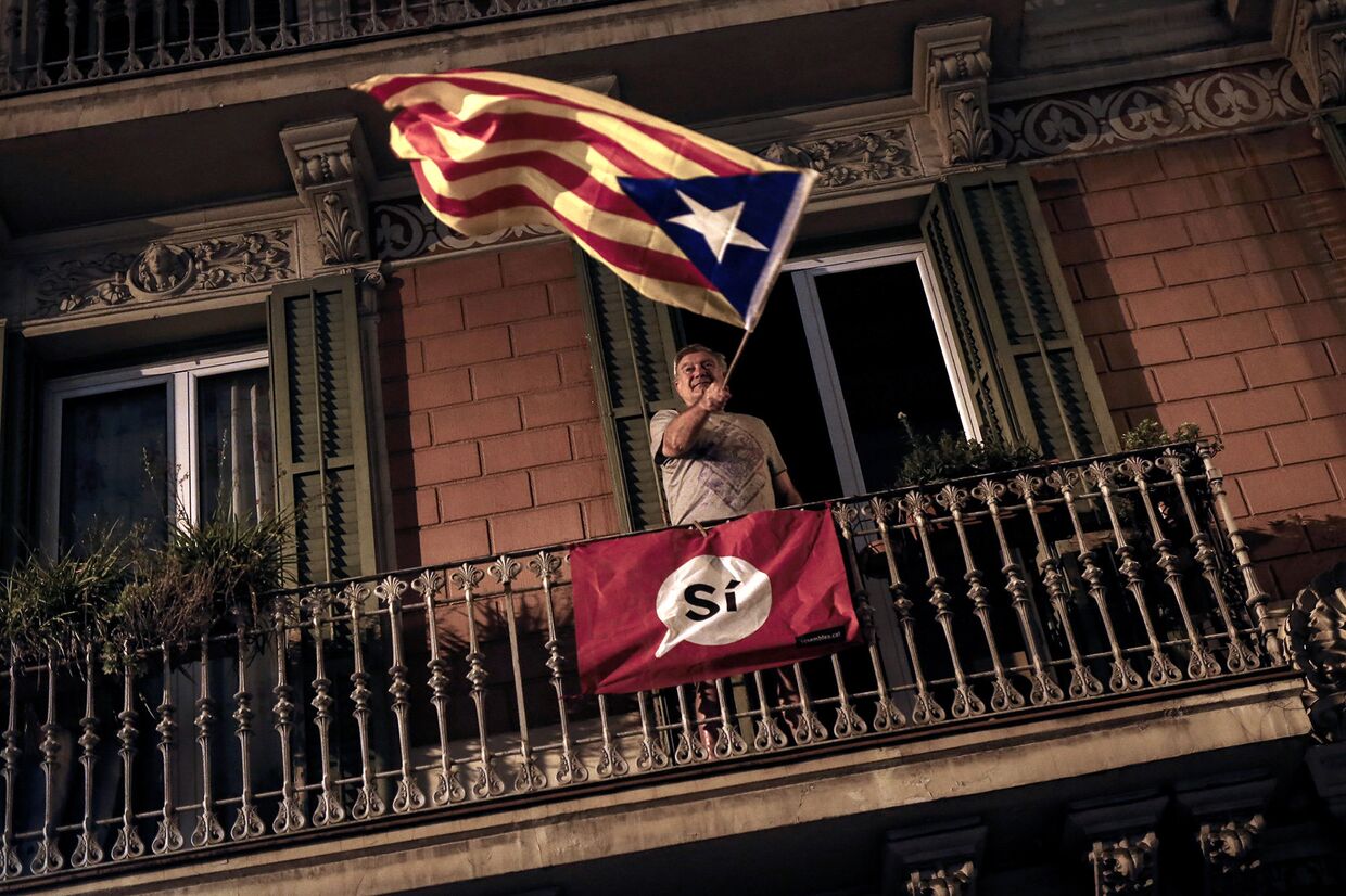 Мужчина держит флаг в поддержку независимости Каталонии в Барселоне