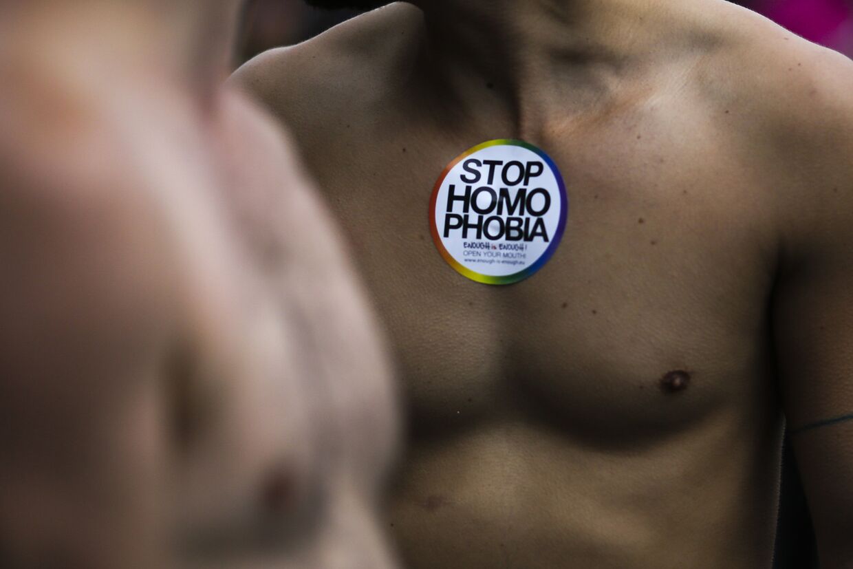 Мужчина с наклейкой, призывающей остановить гомофобию на ежегодном гей-параде в Берлине