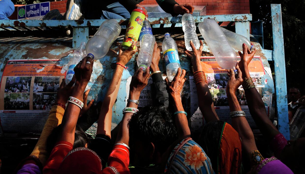 Индийские женщины участвующие в митинге в Нью-Дели, стоят в очереди за питьевой водой