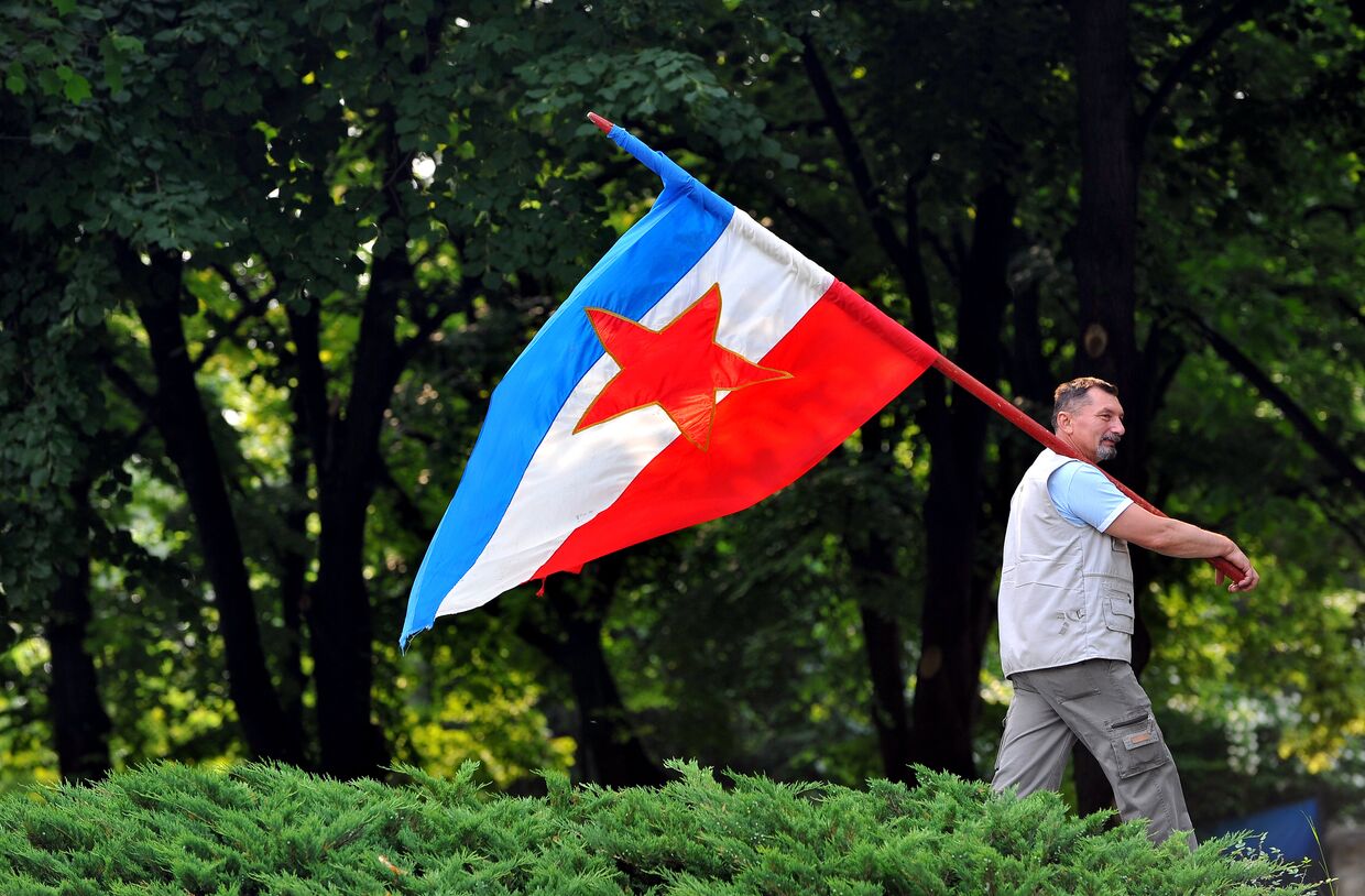 Мужчина с флагом Социалистической Федеративной Республики Югославия в Белграде
