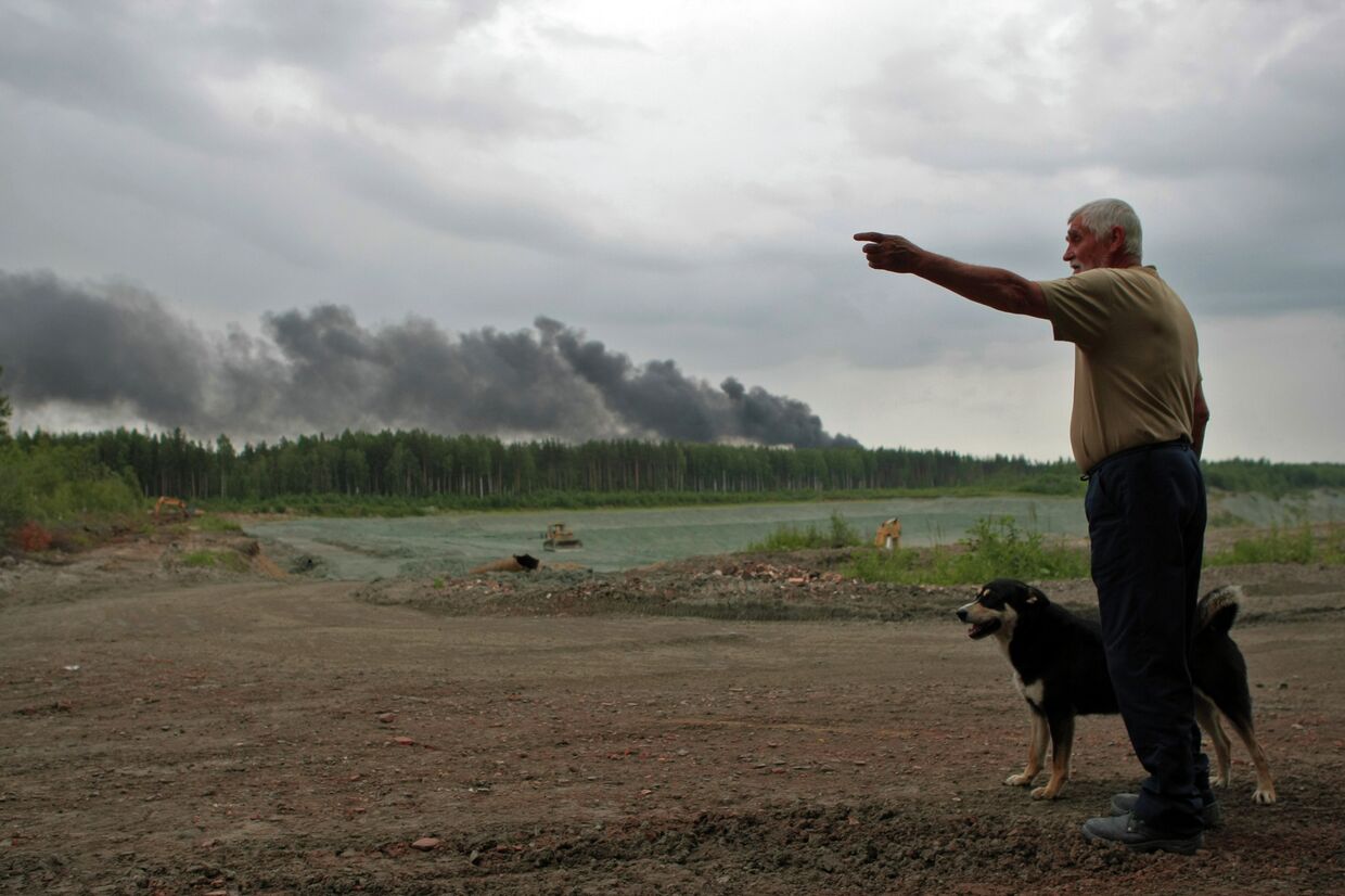 Местный житель отвечает на вопросы журналистов во время пожара на полигоне токсичных отходов «Красный бор» в Ленинградской области