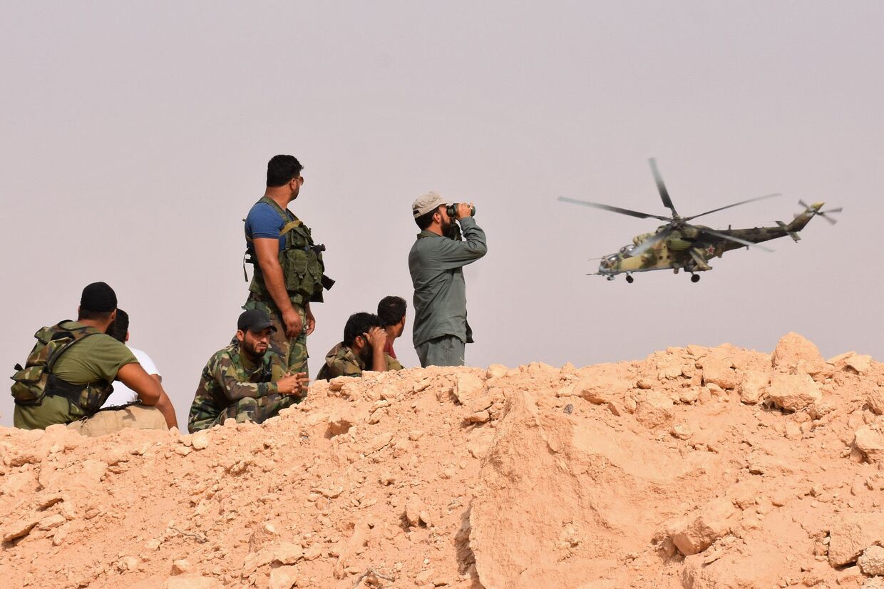 Сирийские военные наблюдают за полетом российского военного вертолета на окраине города Дейр-Эз-Зора