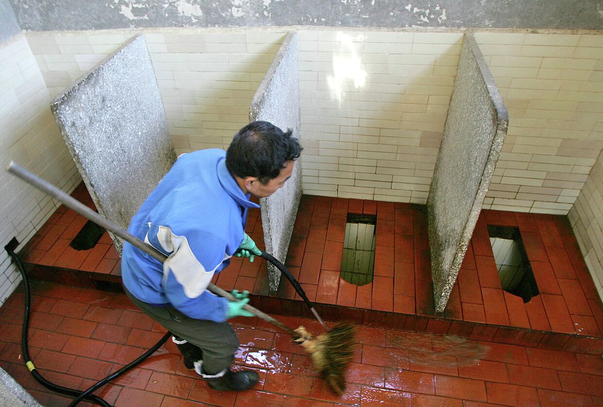 Работник очищает общественный туалет в Китае