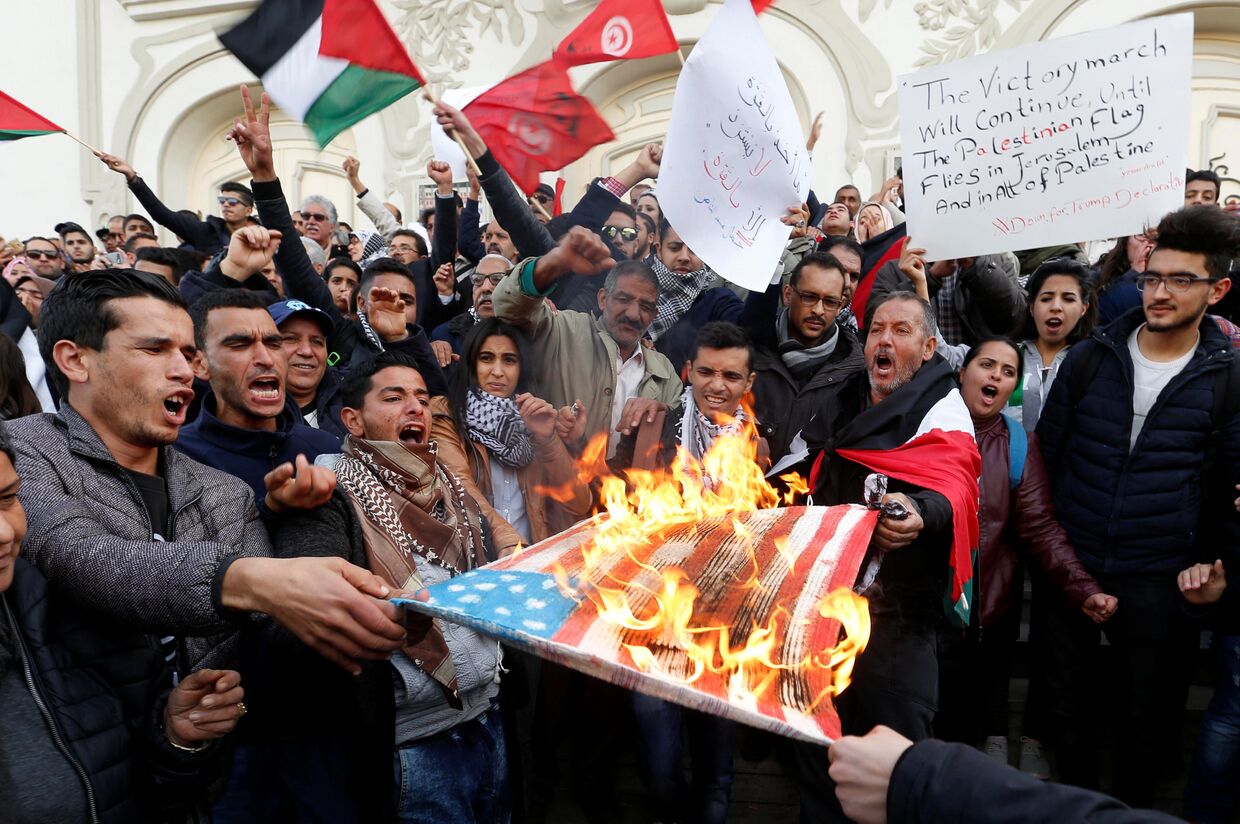 Протестующие сжигают флаг США во время протеста против решения Дональда Трампа признать Иерусалим столицей Израиля в Тунисе. 7 декабря 2017