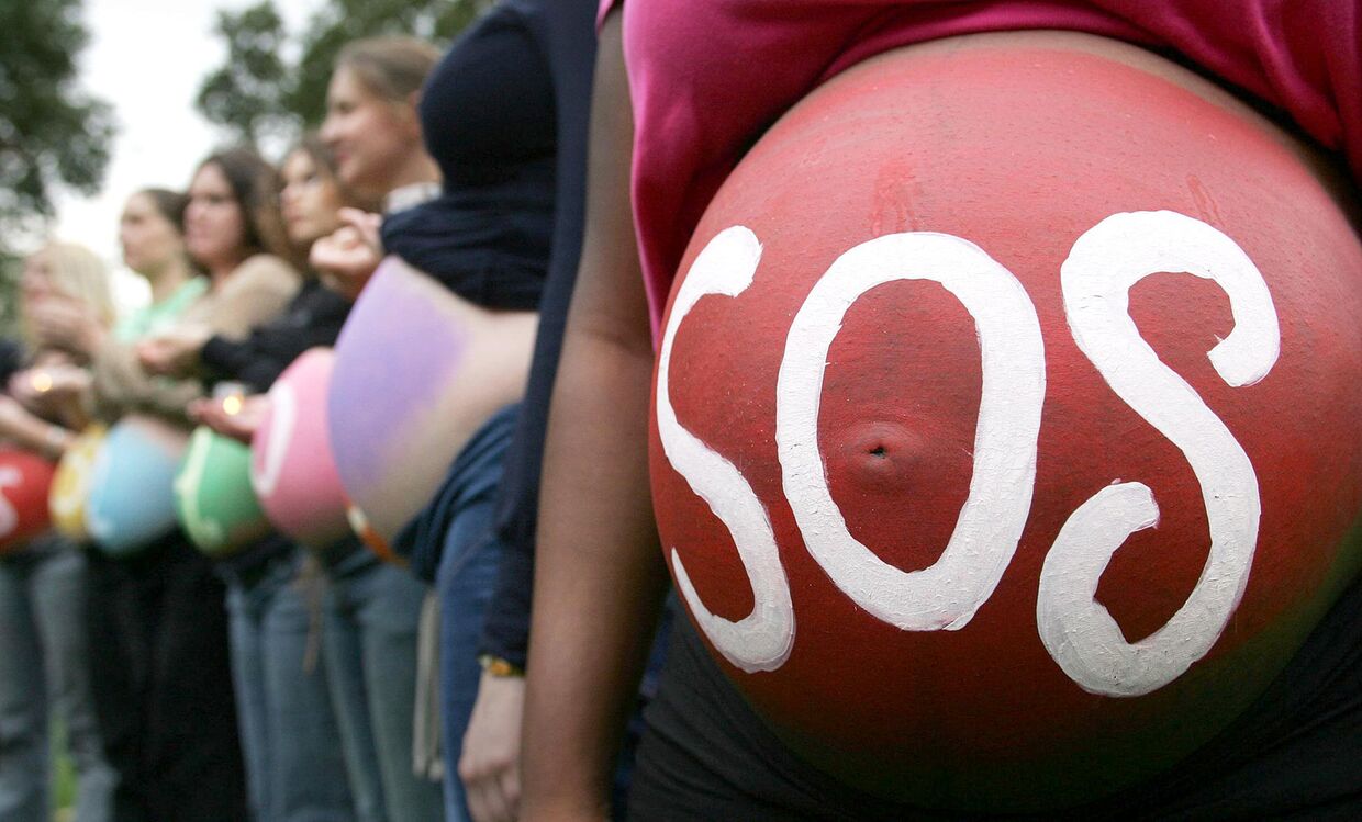 Беременная женщина с надписью SOS на животе на митинге в Лондоне