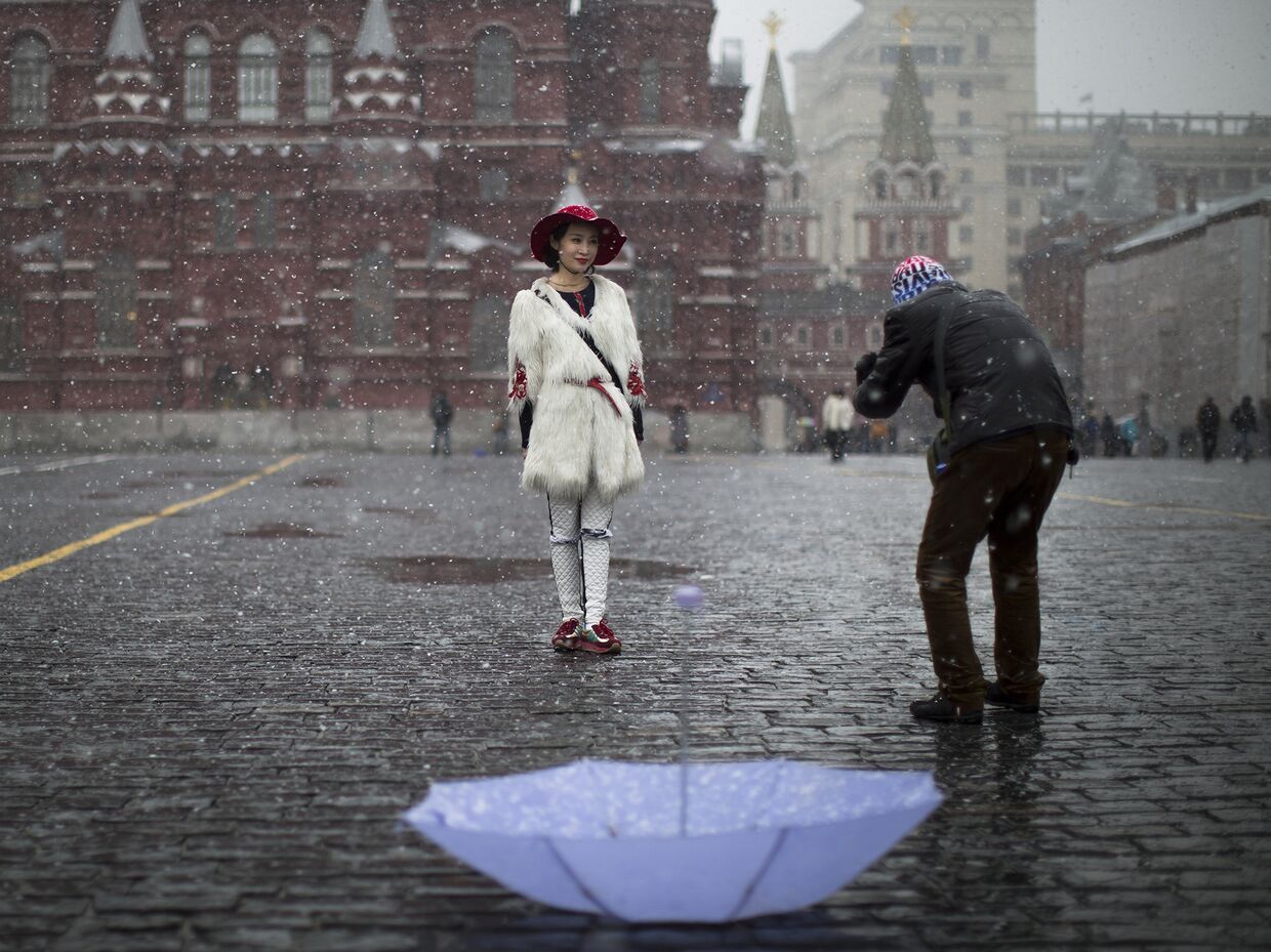 Китайские туристы фотографируются на Красной площади во время снегопада