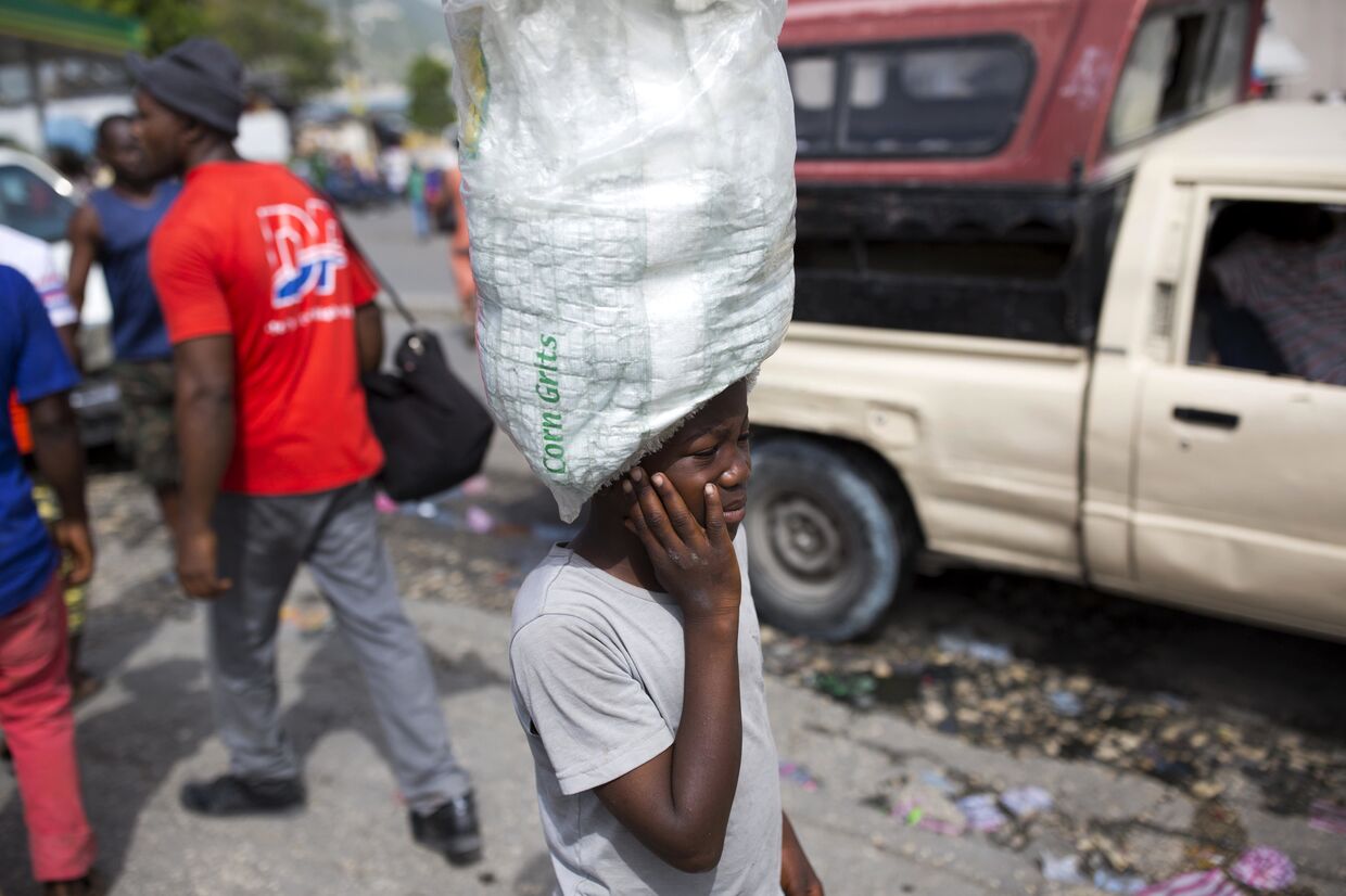Мальчик носит воду, предназначенную для продажи, по улицам Порт-о-Пренс, Гаити