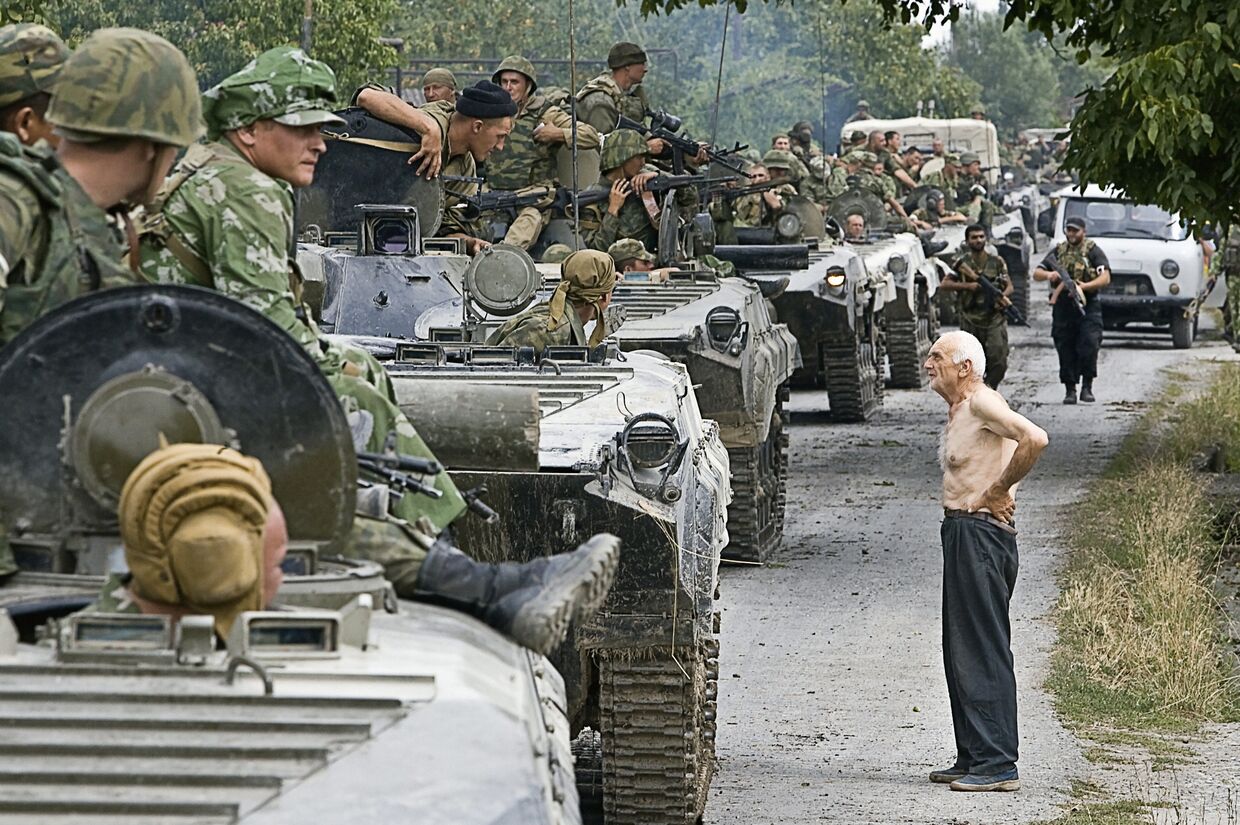 Колонна российских войск, движущихся в место временного лагеря на территории Грузии. Справа - житель Грузии