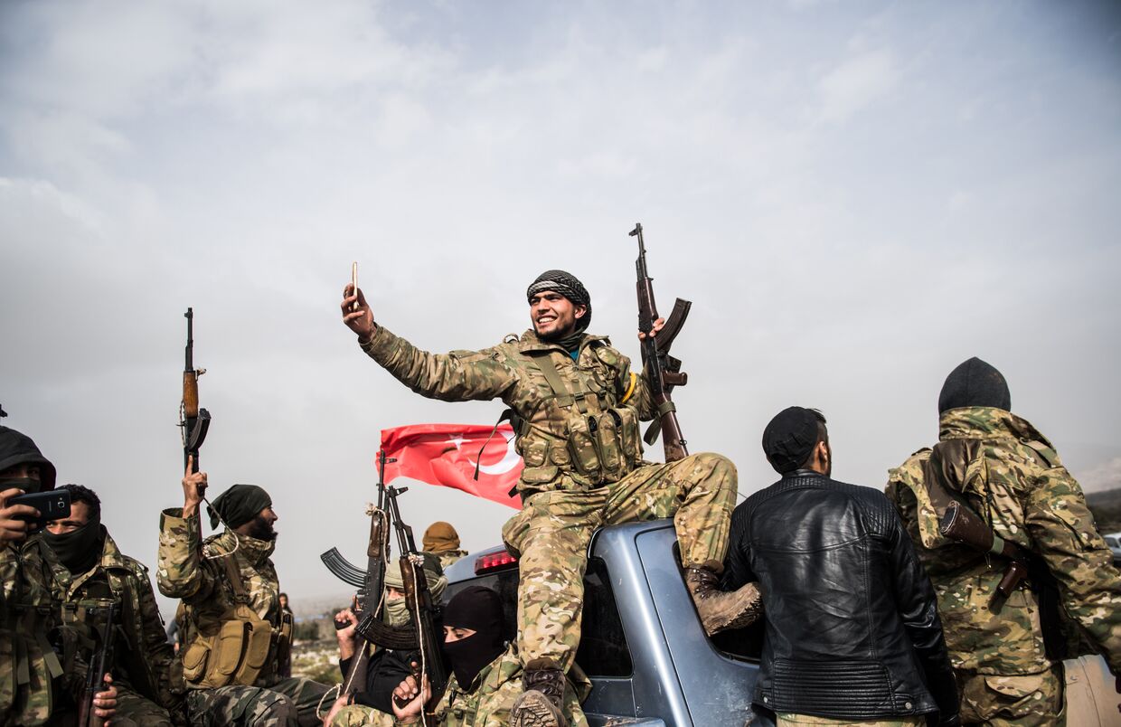 Боец сирийской оппозиции фоторафирует колонну турецких солдат около сирийской границы в Хассе, провинция Хатай. 22 января 2018
