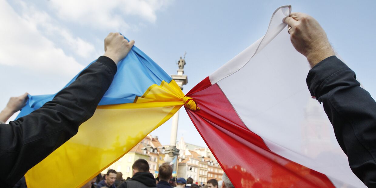 Люди держат связанные флаги Польши и Украины в Варшаве