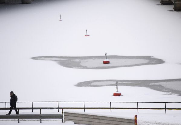 Мужчина идет мимо замерзших вод Стокгольмского порта, Стокгольм, Швеция