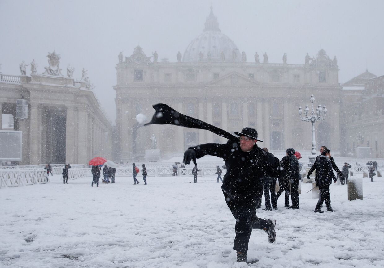 Молодой священник бросает снежок во время сильного снегопада на площади Святого Петра в Ватикане