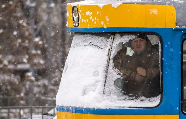 Мужчина смотрит в окно трамвая во время сильного снегопада в Софии, Болгария