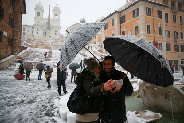 Пара перед заснеженным Колизеем во время снегопада в Риме, Италия