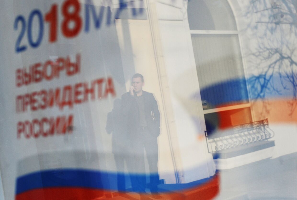 Отражение в окне баннера с информацией о выборах президента России 18 марта 2018.