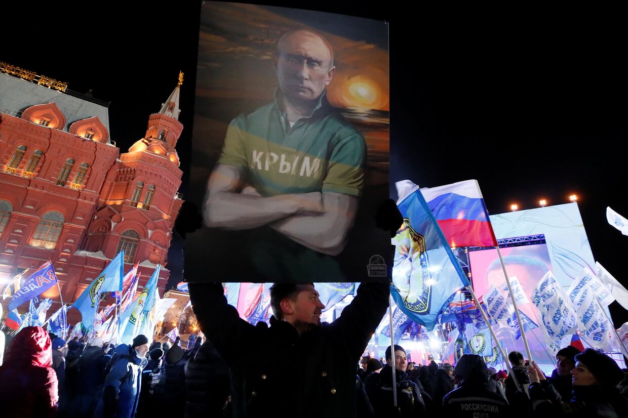 Мужчина держит плакат с изображением Владимира Путина