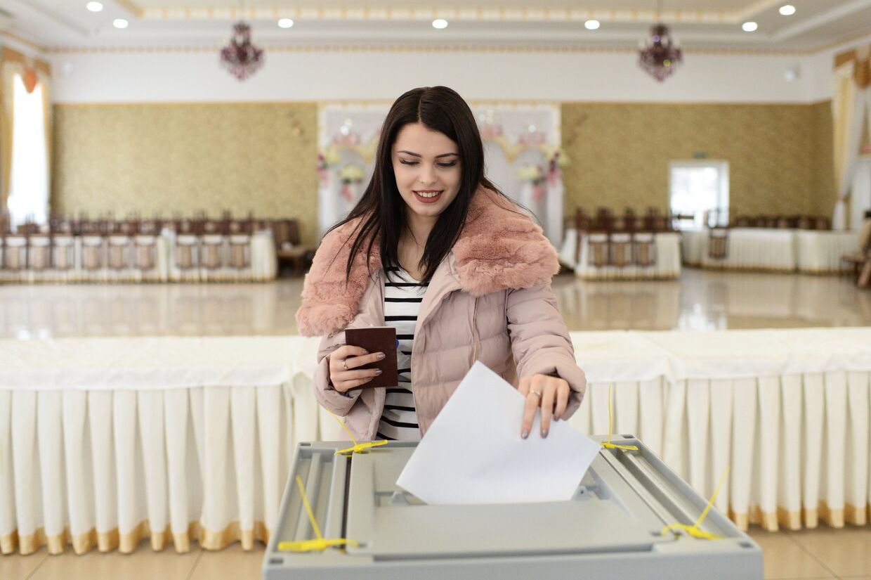 Девушка опускает бюллетень в урну на выборах президента РФ на избирательном участке в Бахчисарае. 18 марта 2018