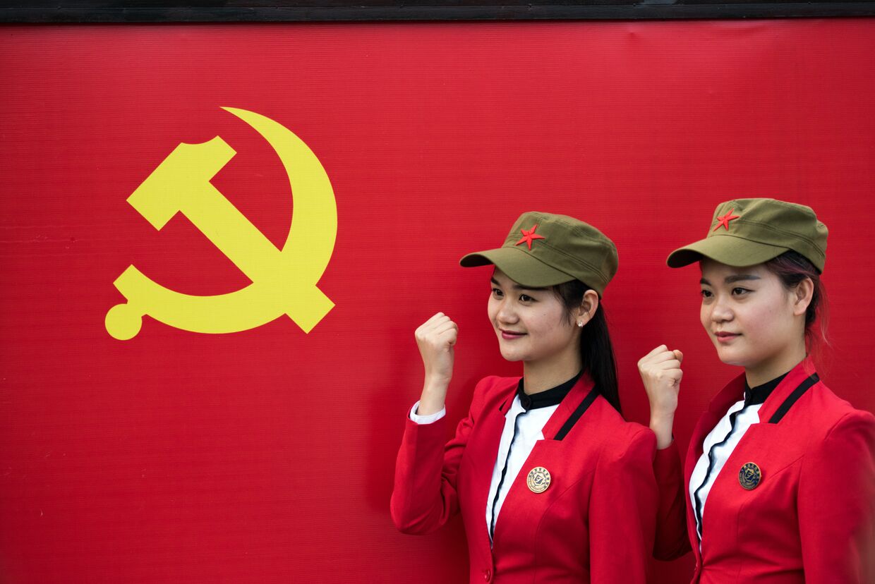 Девушки фотографируются с флагом Коммунистической партии Китая в Шаошане