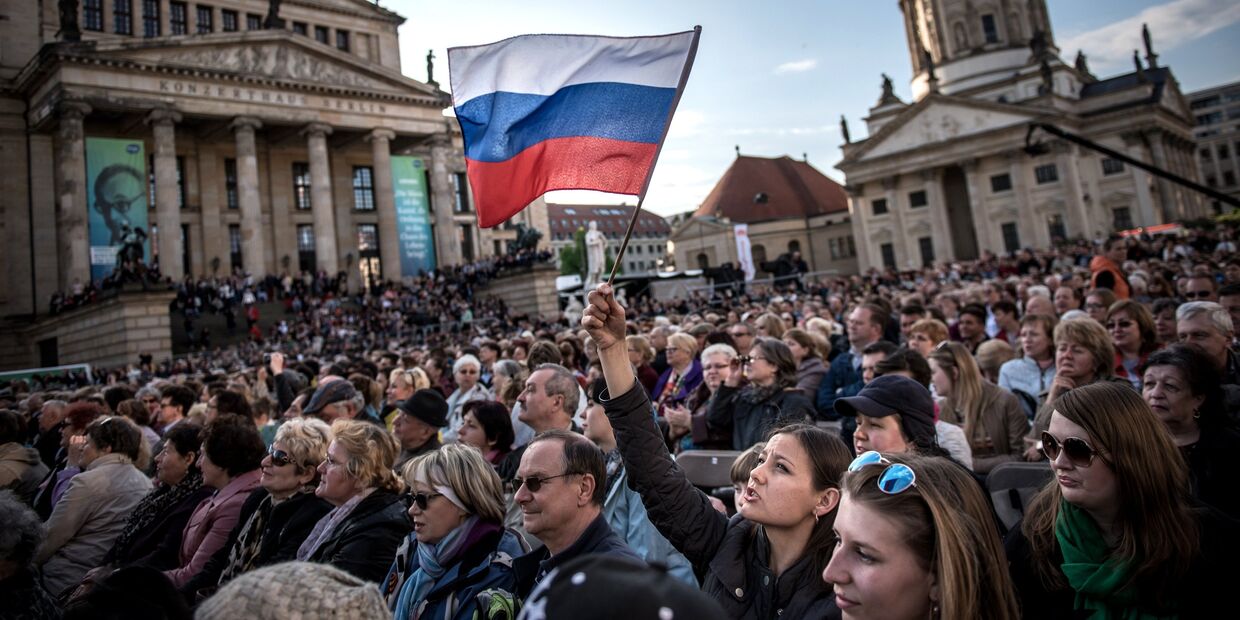 Посетители концерта Песни Победы на площади Жандарменмаркт в центре Берлина