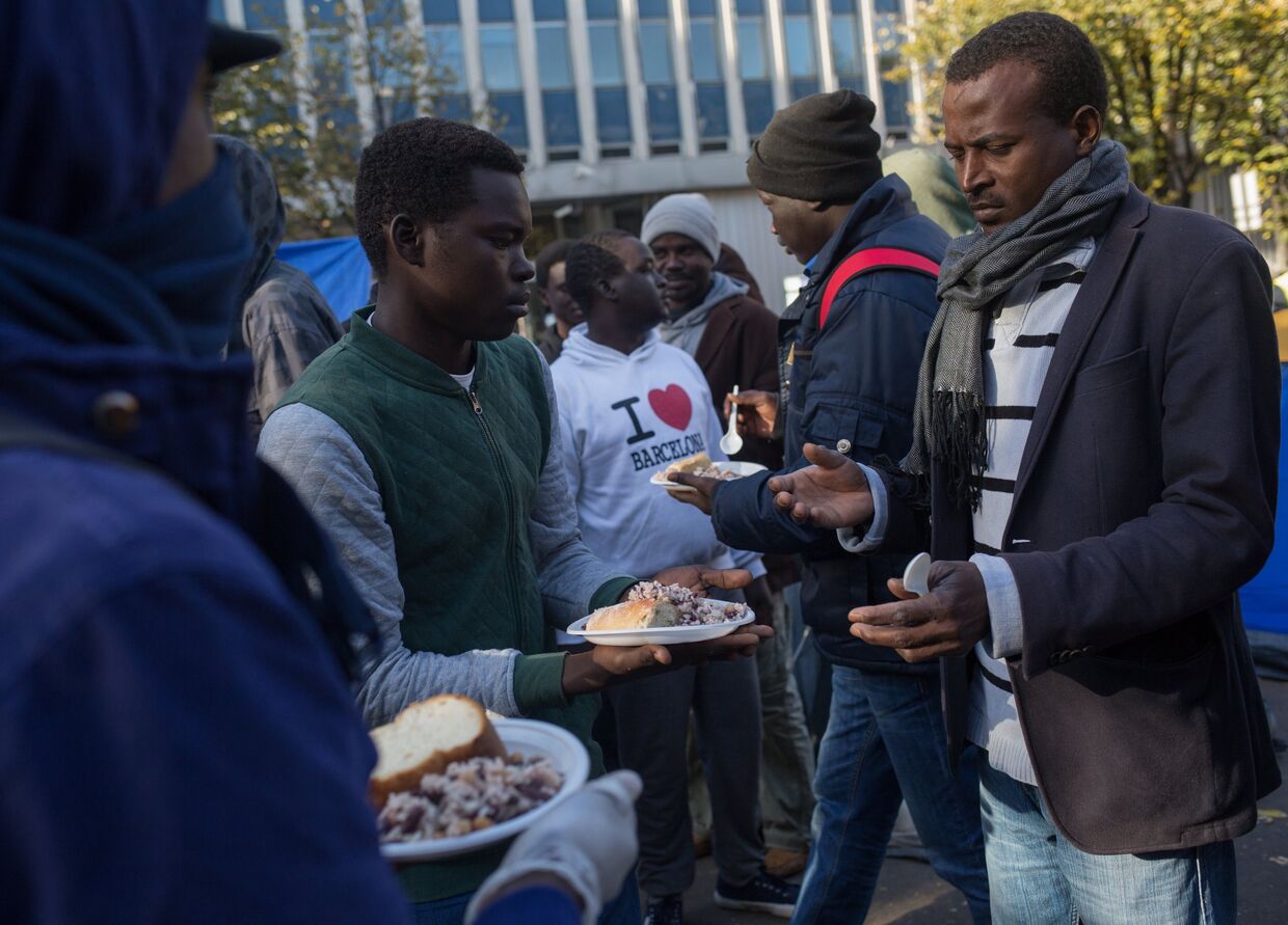 Раздача еды в лагере мигрантов в районе Сталинград в Париже