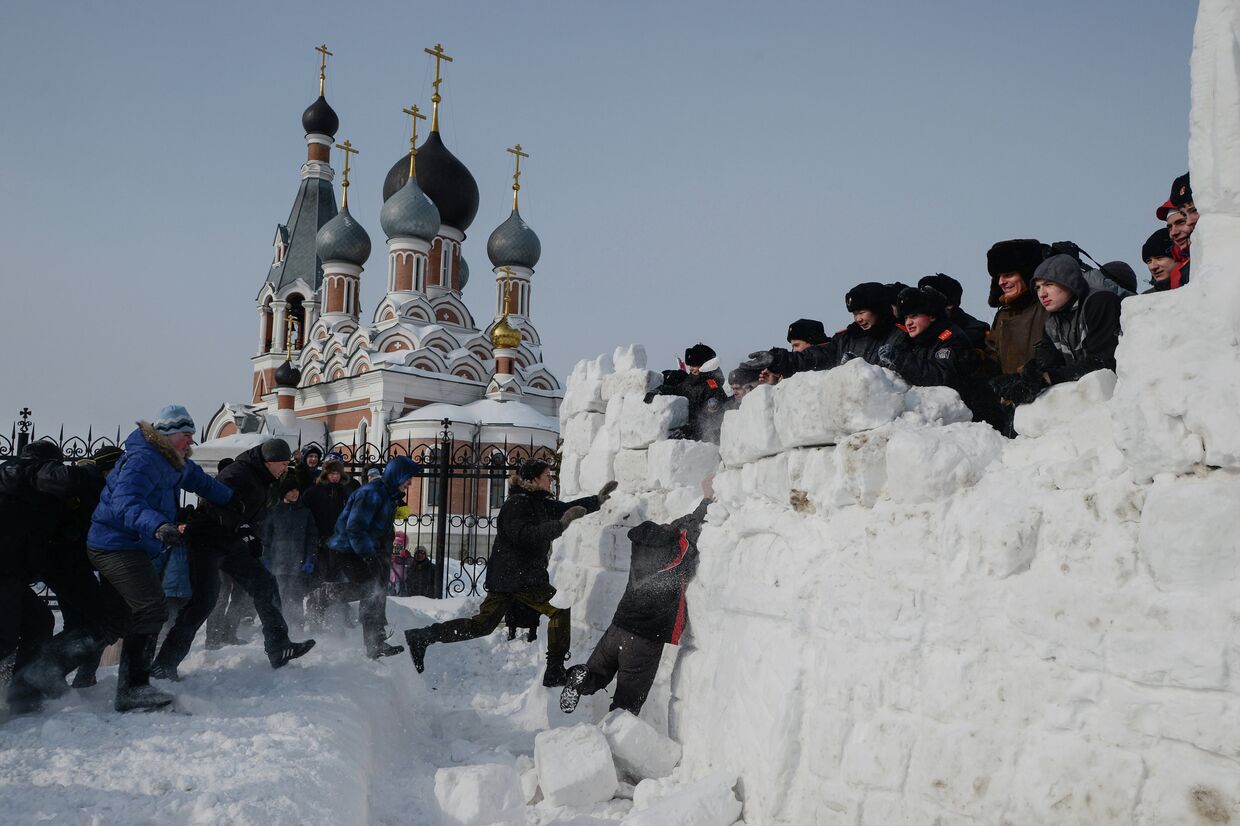 Взятие снежного городка во время Масленичных гуляний на площади Преображенского кафедрального собора в Бердске Новосибирской области