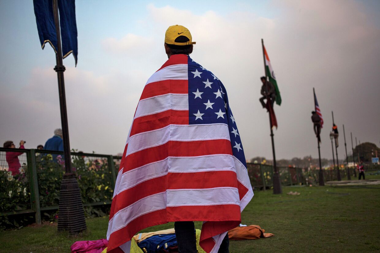 Индийский рабочий с американским флагом в Нью-Дели накануне приезда президента США Барака Обамы