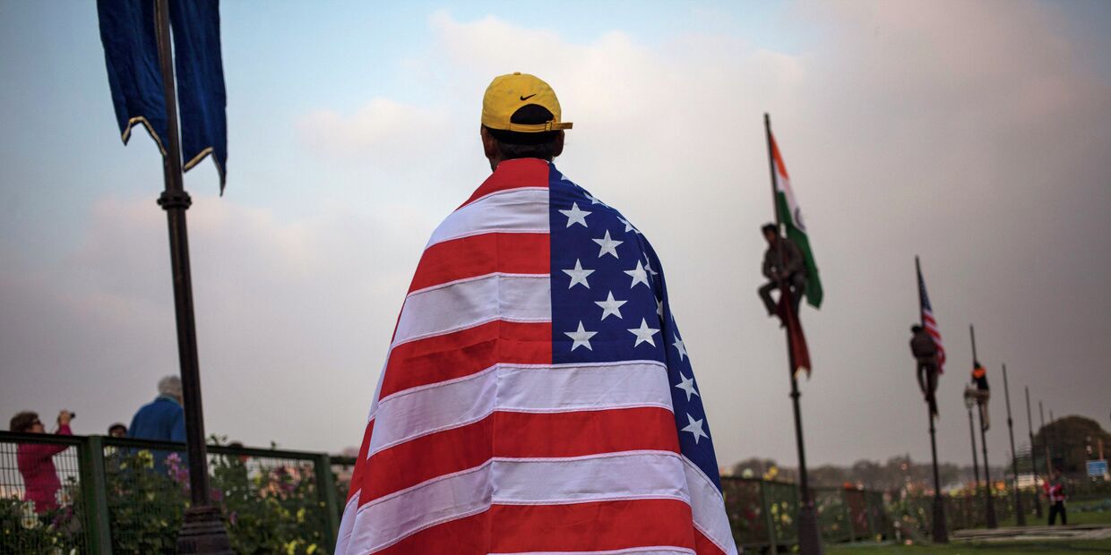 Индийский рабочий с американским флагом в Нью-Дели накануне приезда президента США Барака Обамы