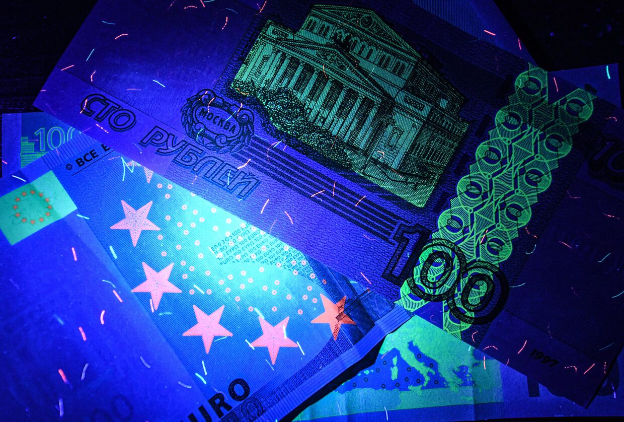 Рубли и евро: денежные купюры под ультрафиолетовым освещением