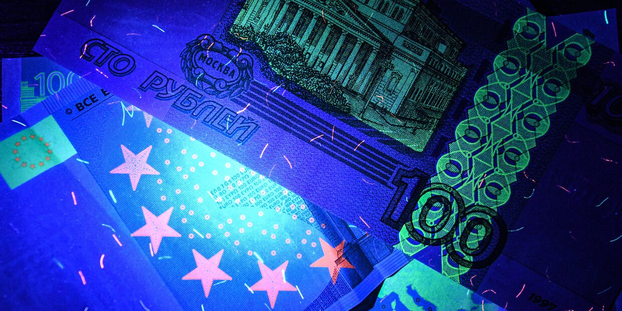 Рубли и евро: денежные купюры под ультрафиолетовым освещением