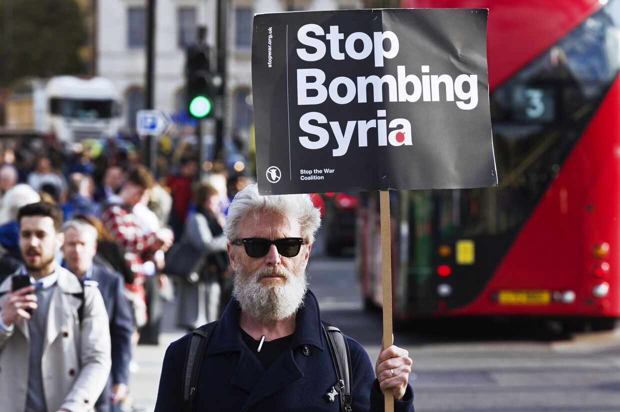 Мужчина держит плакат, призывающей не бомбить Сирию, на акции протеста против ударов по Сирии в Лондоне