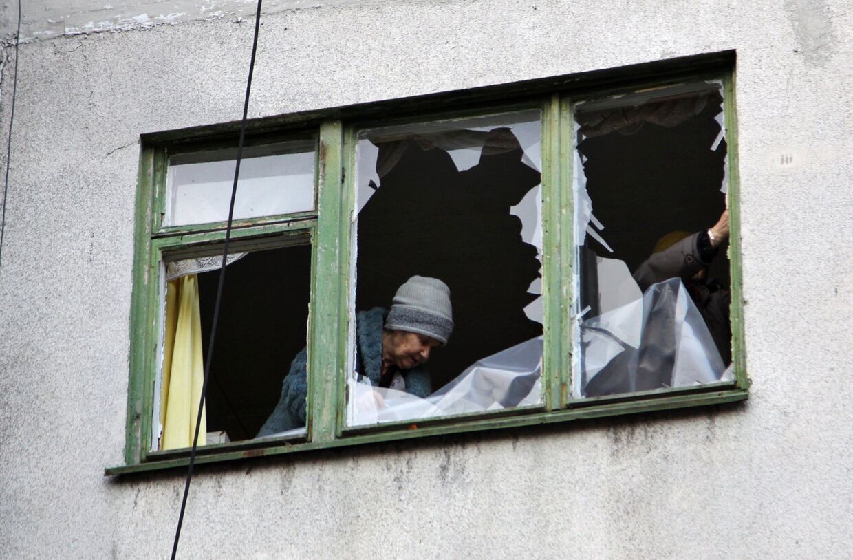 Женщина у окна жилого дома в центре города Ясиноватая, пострадавшего в результате обстрела