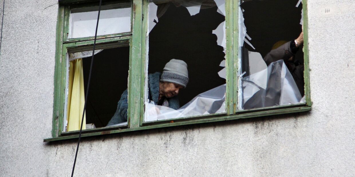 Женщина у окна жилого дома в центре города Ясиноватая, пострадавшего в результате обстрела